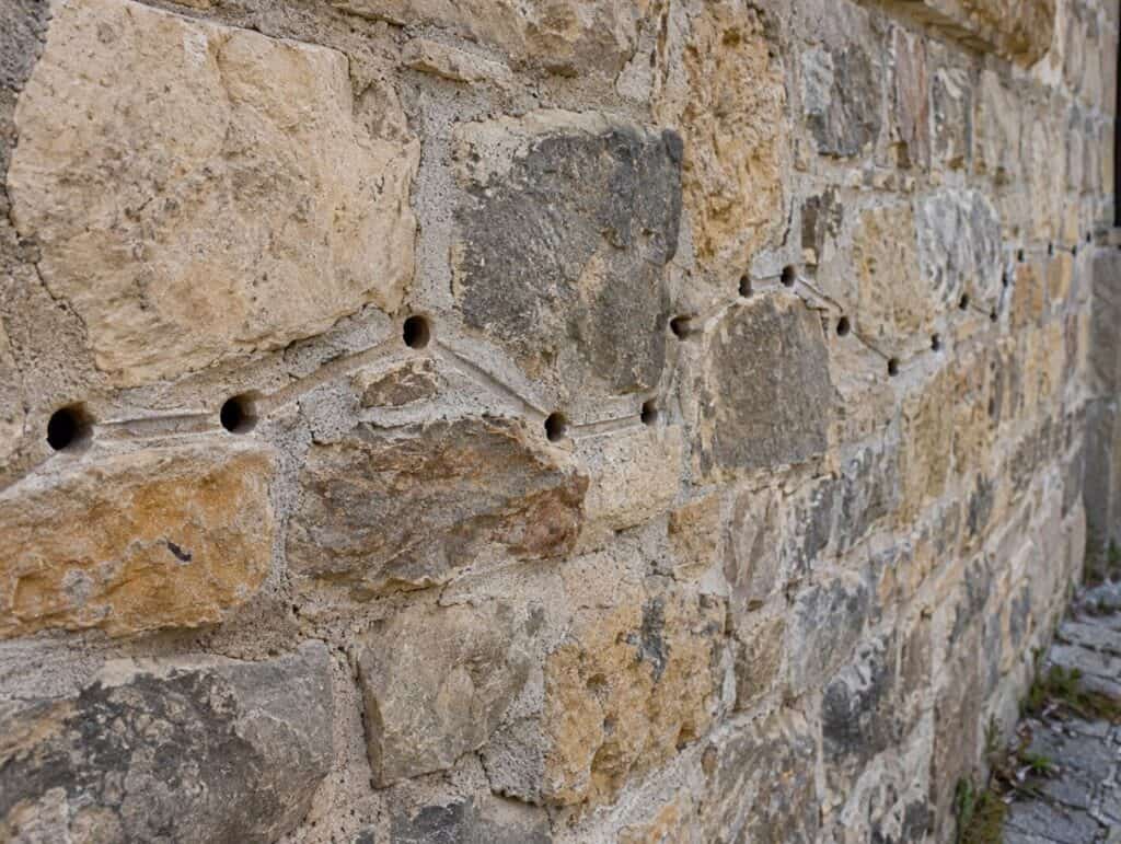 Schema di muro in pietra visto frontalmente e in sezione: la fuga esterna non prosegue rettilinea nel nucleo